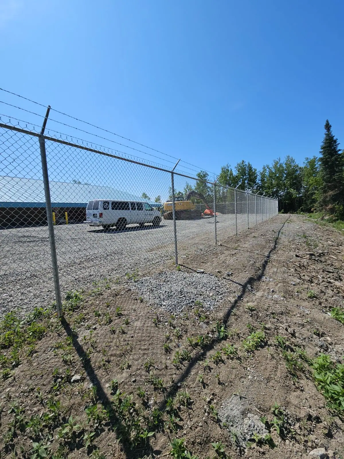 Security fence topped with barbed-wire arms