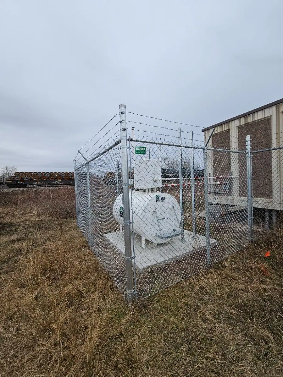 Tank enclosure with a barbed-wire top